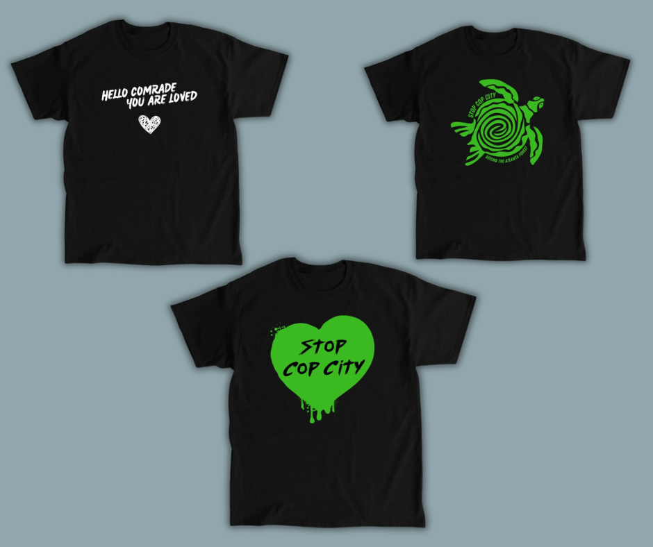 image is of three black tshirts one says hello comrade, you are loved, the second is an image of a sea turtle with stop cop city defend the atlanta forest along the edge of the shell and the third tshirt has a spraypainted heart with the words Stop Cop City